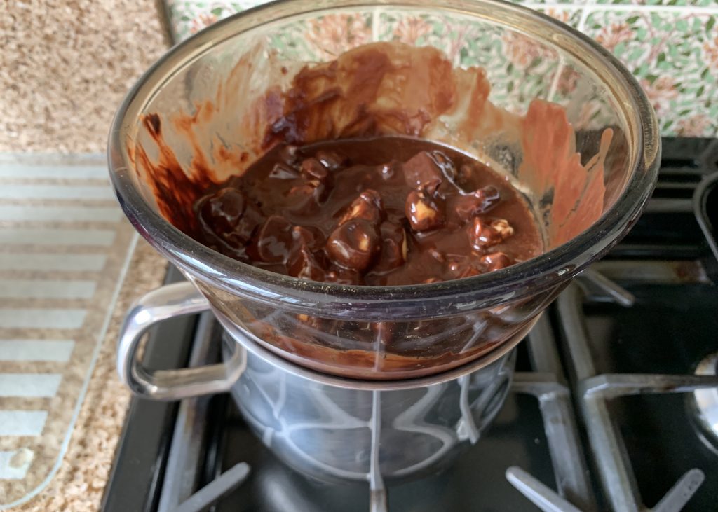 Melted chocolate and butter in a large glass dish sat over a pan of boiling water