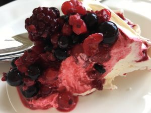 Slice of meringue pavlova with summer fruits and fresh cream