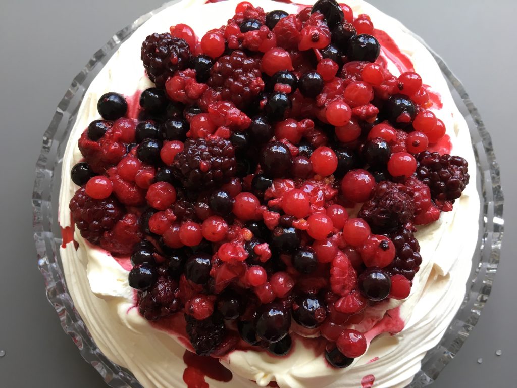 Gluten free meringue pavlova filled with cream and summer fruit berries