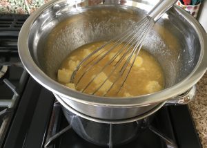 Ingredients for lemon curd in a stainless steel bowl over a pan of simmering water