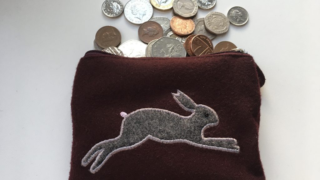 Felt purse with a hare on the front and coins tipped out of it. How to Save blog