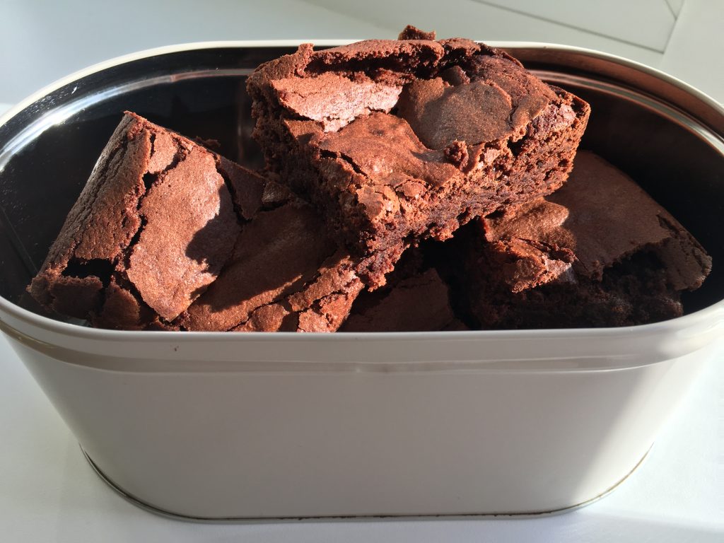Gluten free brownies cut into squares and in a cream tin