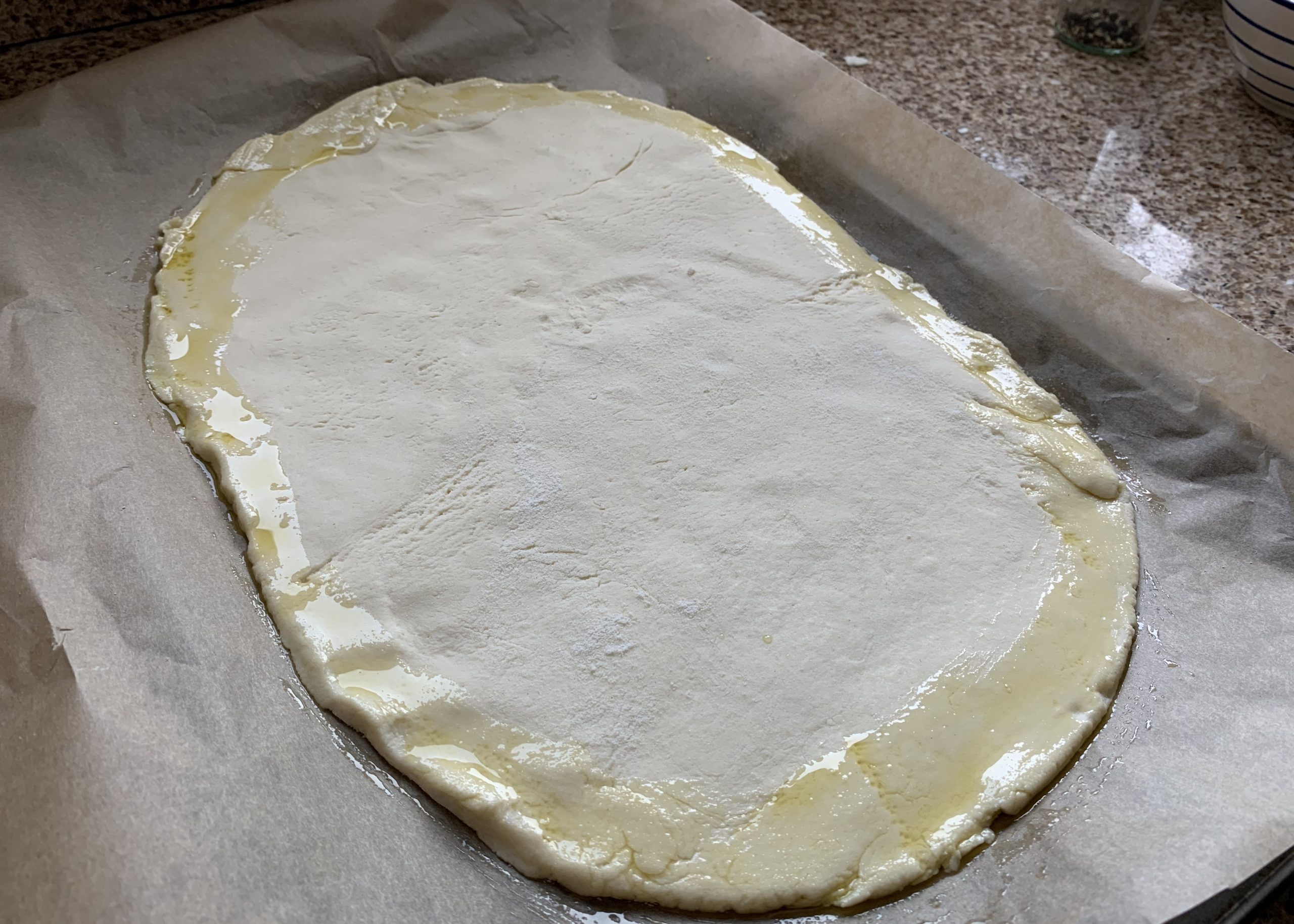 Gluten free pizza dough brushed around the edges with olive oil
