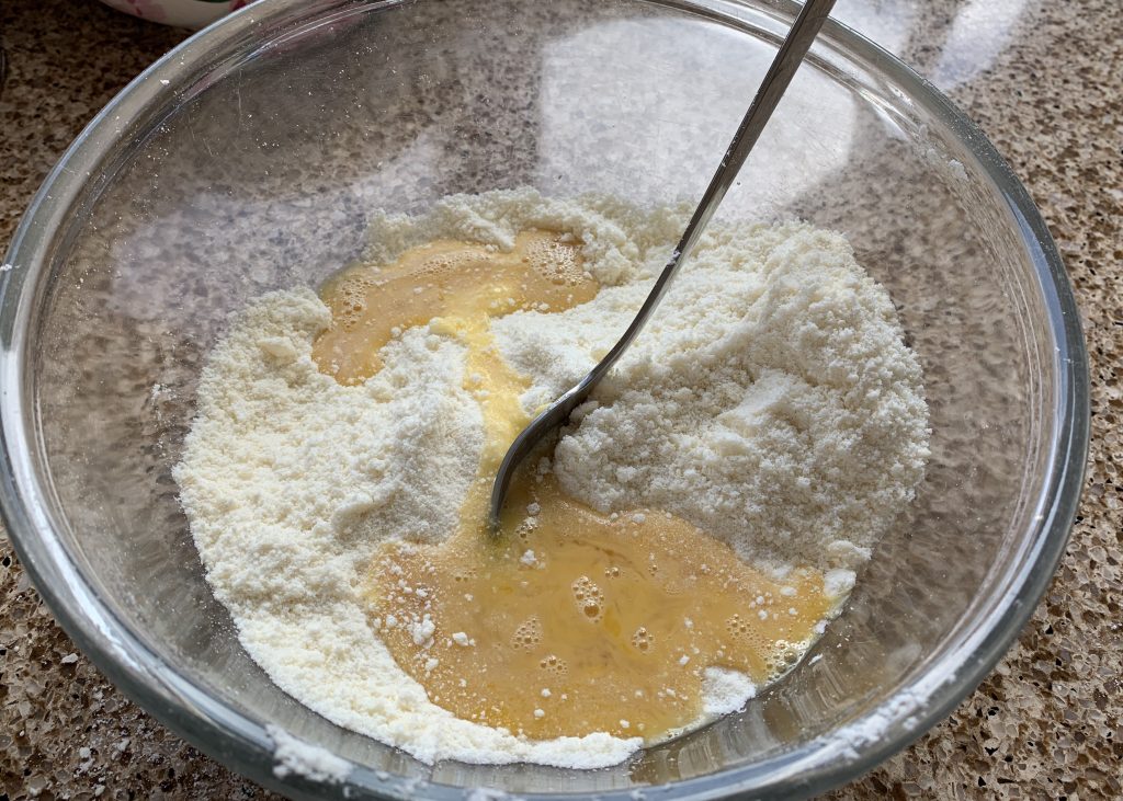 Gluten free flour and beaten egg in a glass bowl