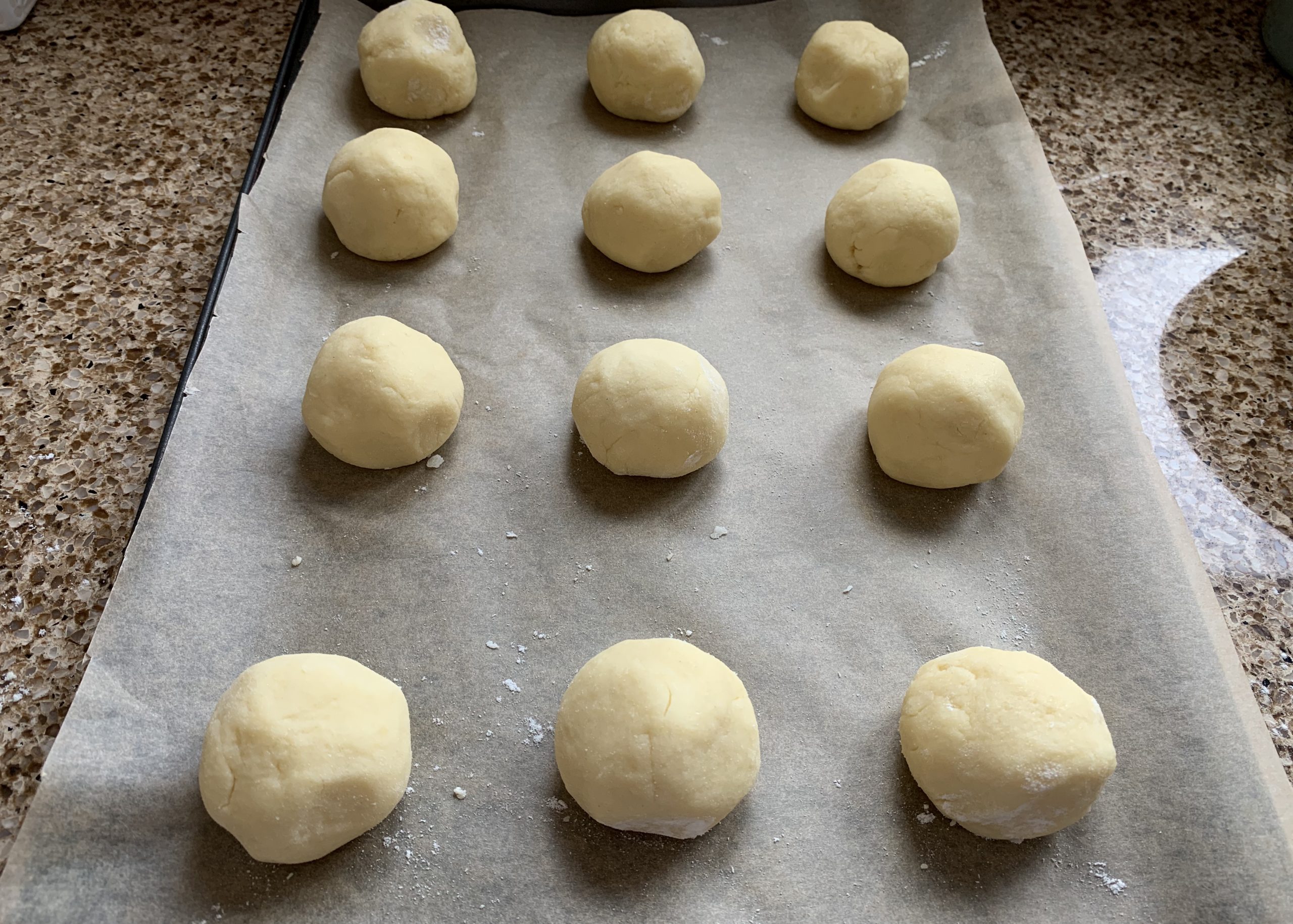 Balls of raspberry bun dough mixture a baking tray