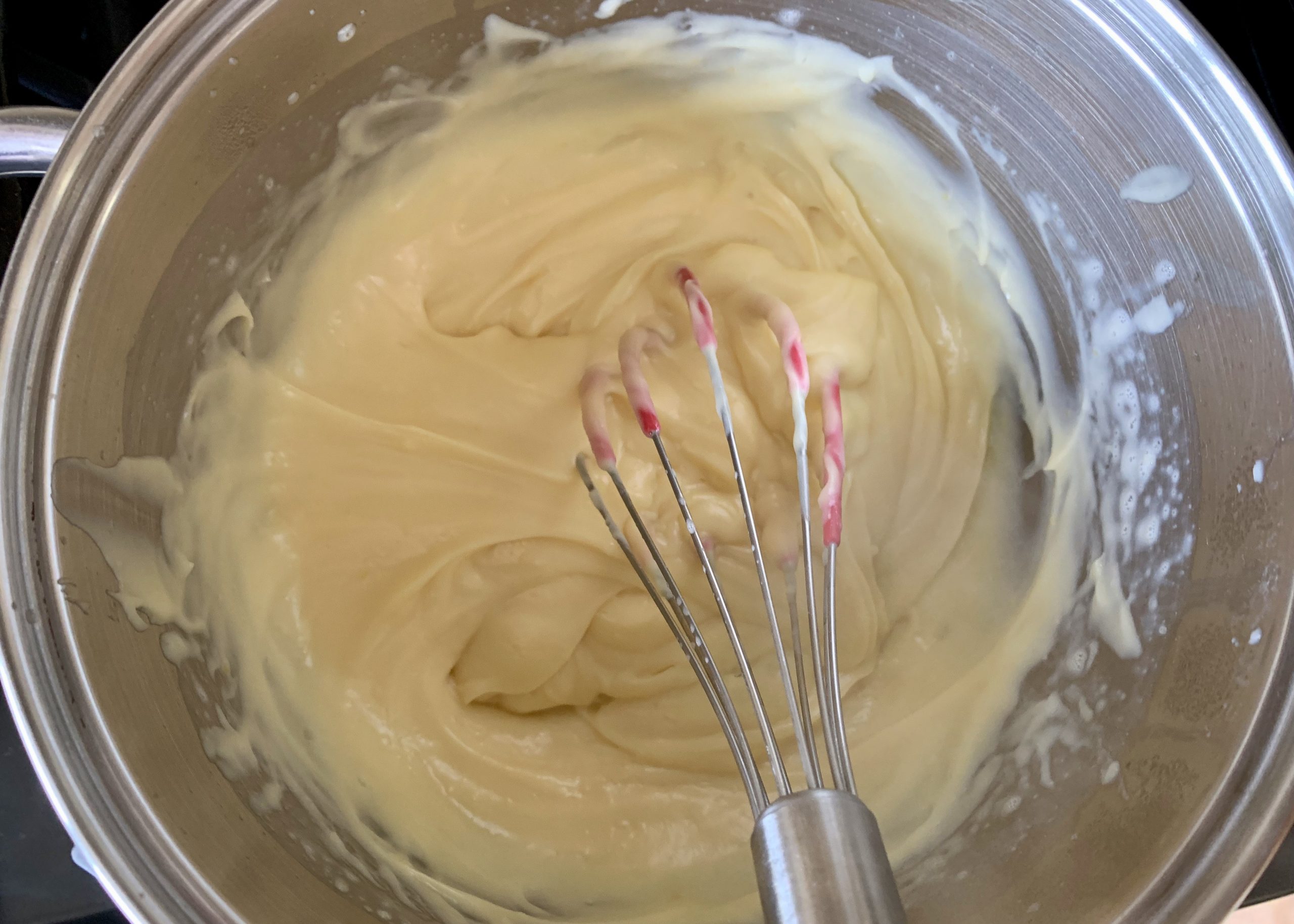 Pastry cream in a pan with a whisk