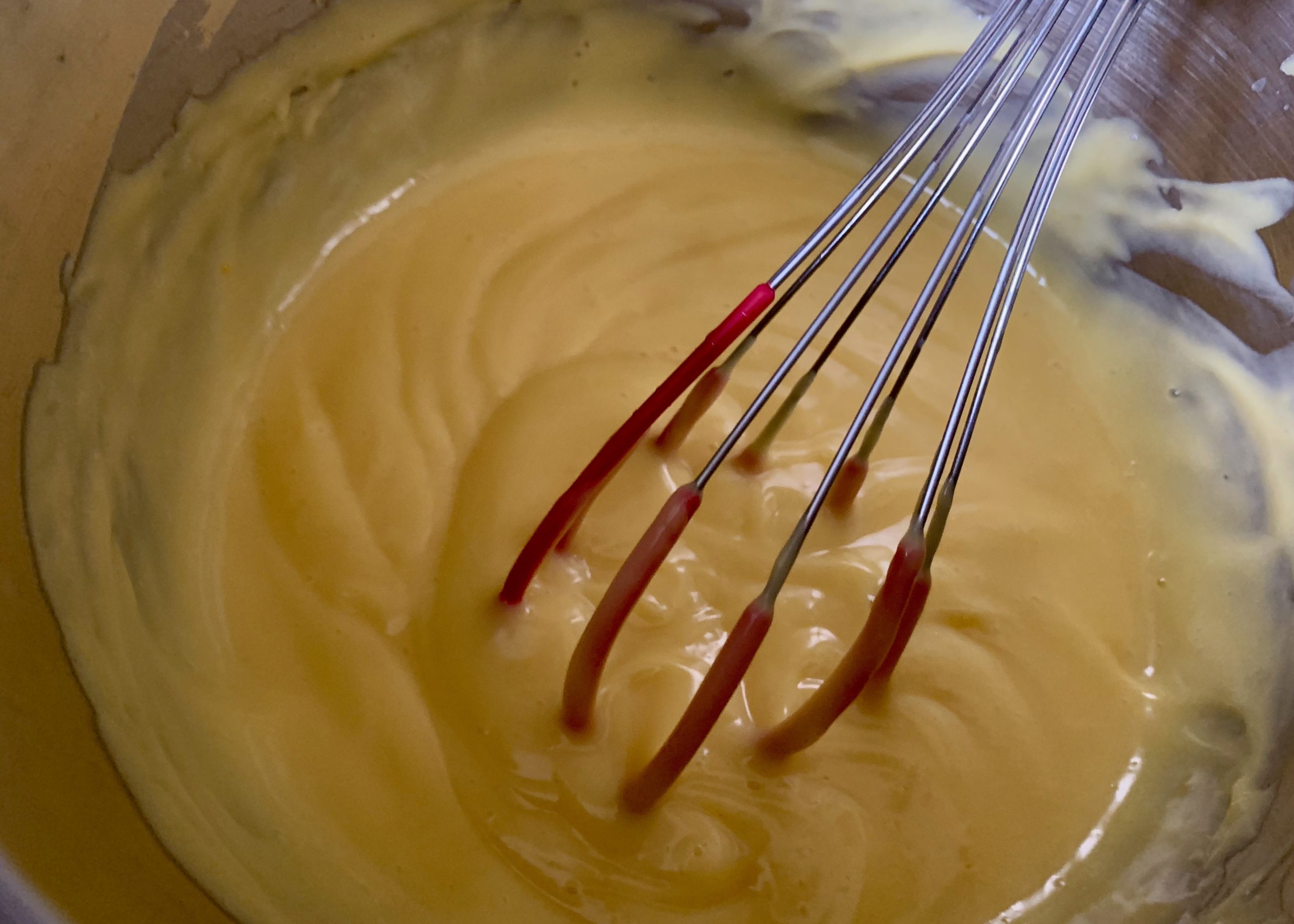 Custard in a saucepan with a whisk