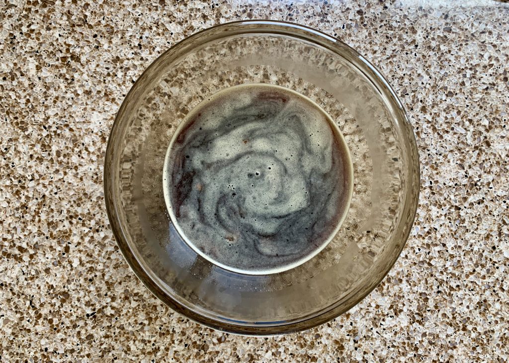 A glass bowl containing dates and hot black coffee