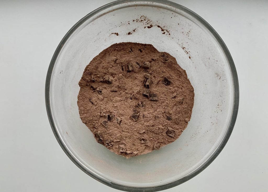 Dry ingredients needed for banana chocolate muffins in a glass bowl f