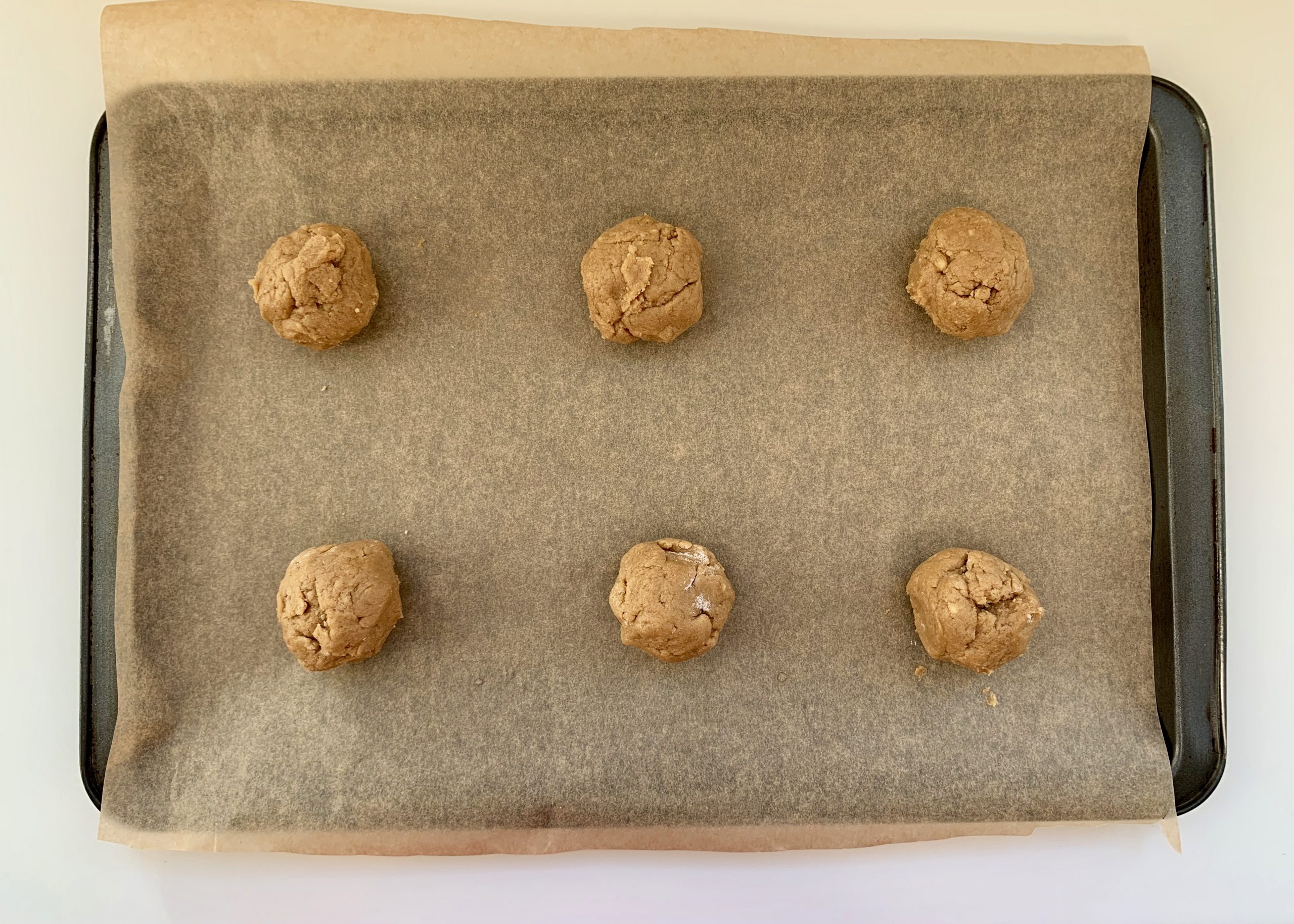 Balls of gluten free ginger biscuit dough on a tray