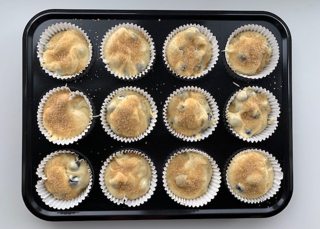 Gluten free blueberry muffin mixture in muffin cases in a muffin tin
