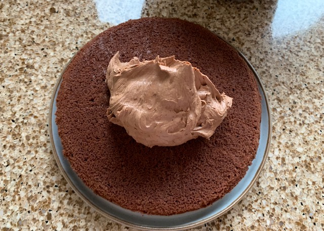 A spoonful of chocolate buttercream on a layer of gluten free chocolate sponge