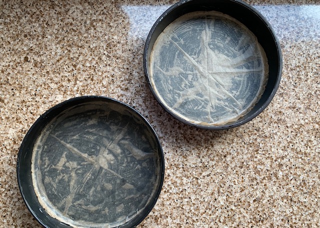 two greased and lined sandwich tins