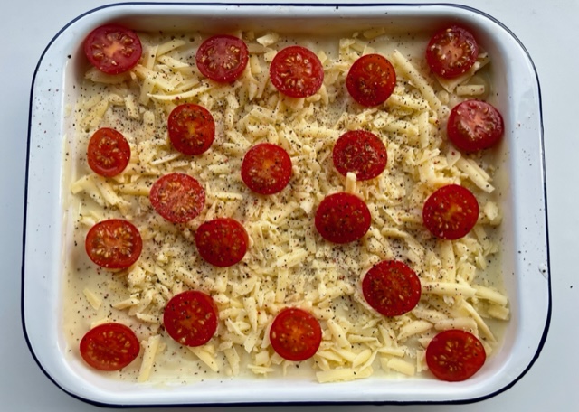 Macaroni cheese topped with grated cheese and tomatoes