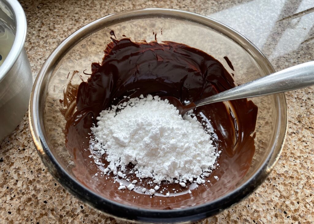 Melted chocolate and icing sugar in a bowl