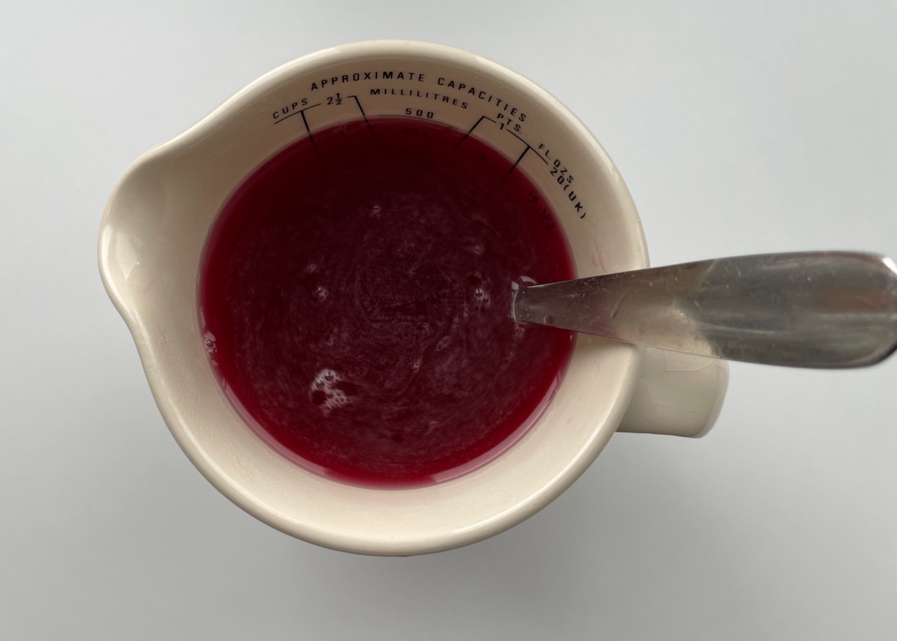 Disolved raspberry jelly in a jug