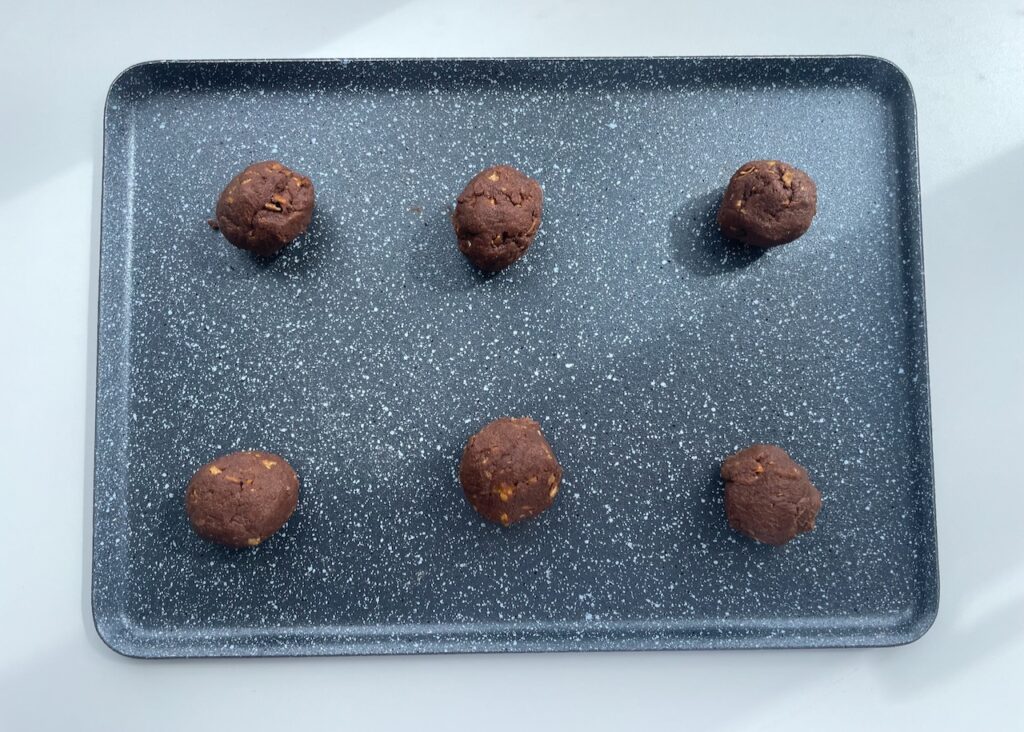 Balls of gluten free chocolate biscuit dough formed into balls on a baking tray